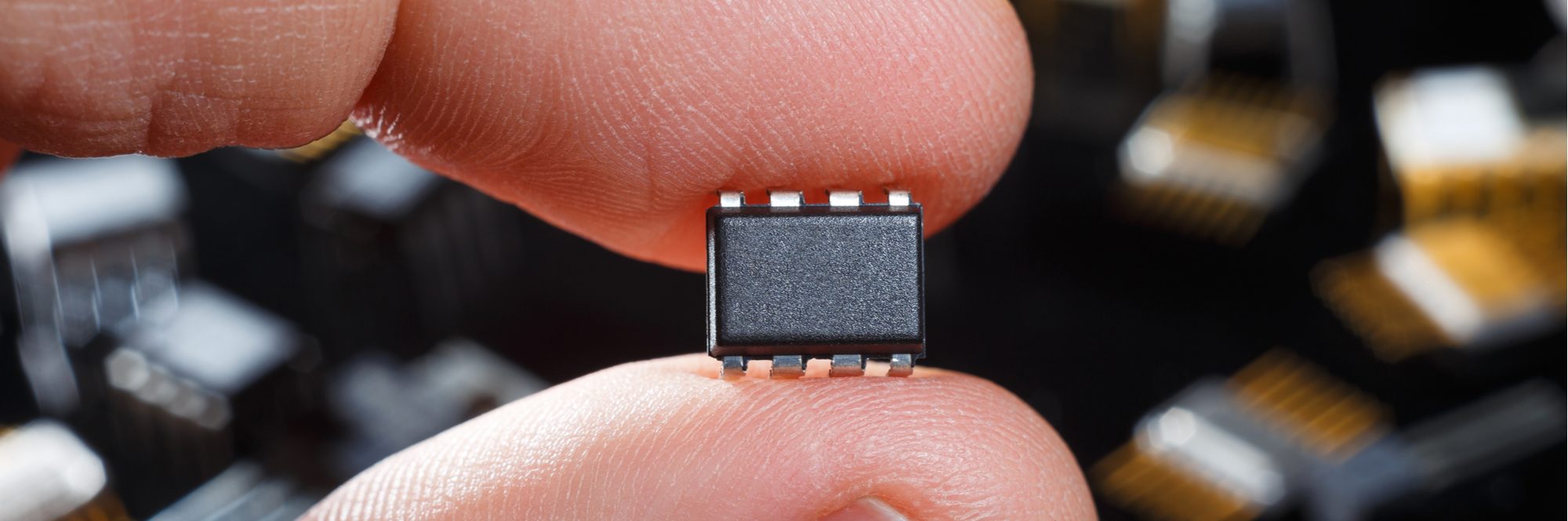 Electronic microchip with fingers close-up. Man hand holds microcircuit.